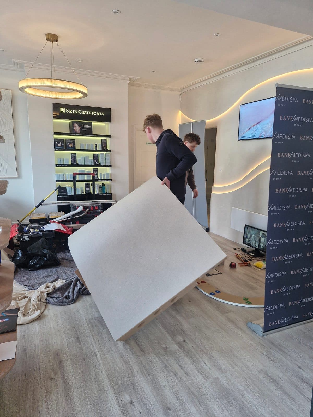 A curved reception desk panel being carried into Bank Medi Spa