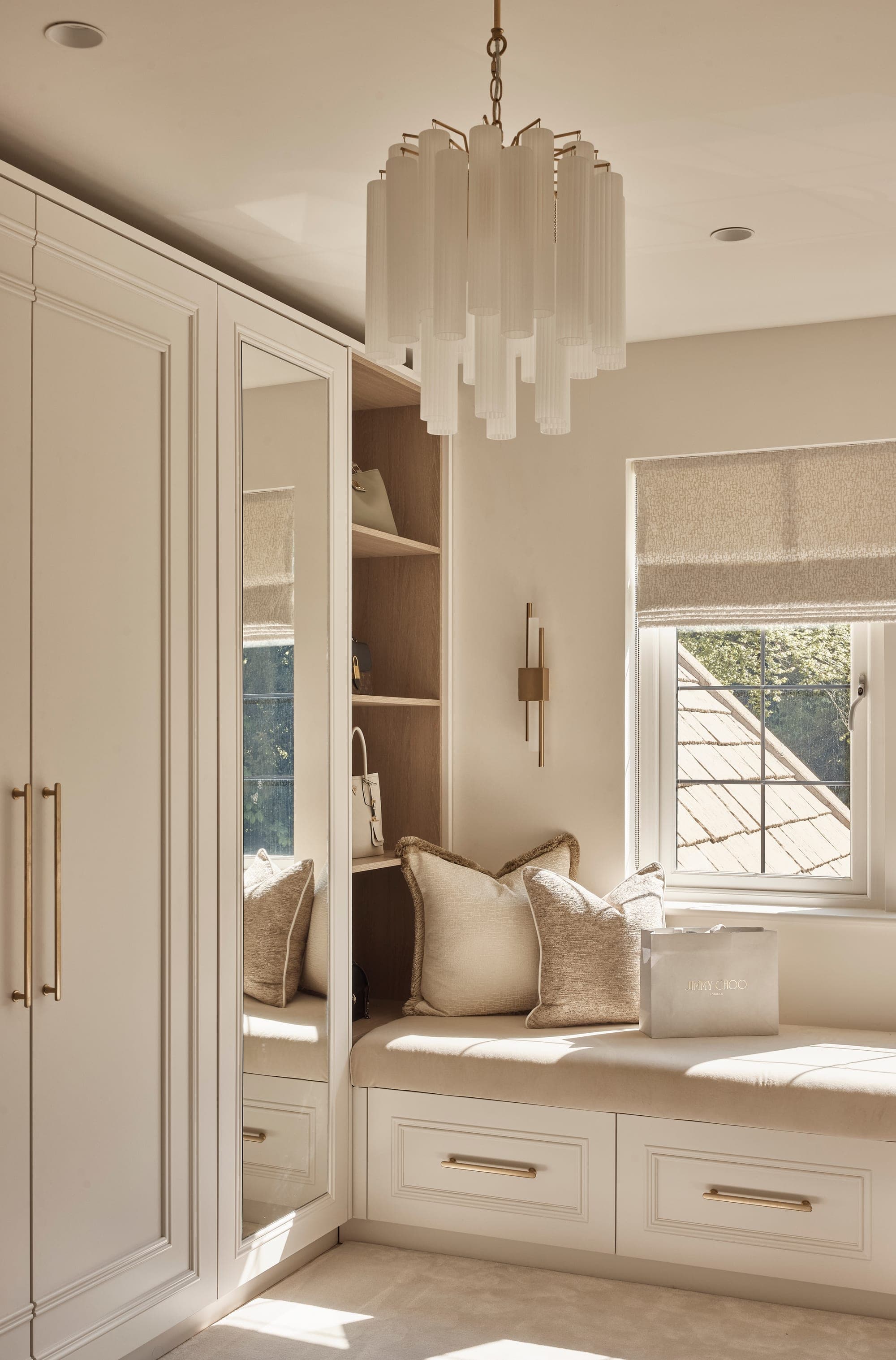 A bespoke dressing room with fitted wardrobes and a cushioned window seat in a Cheshire home