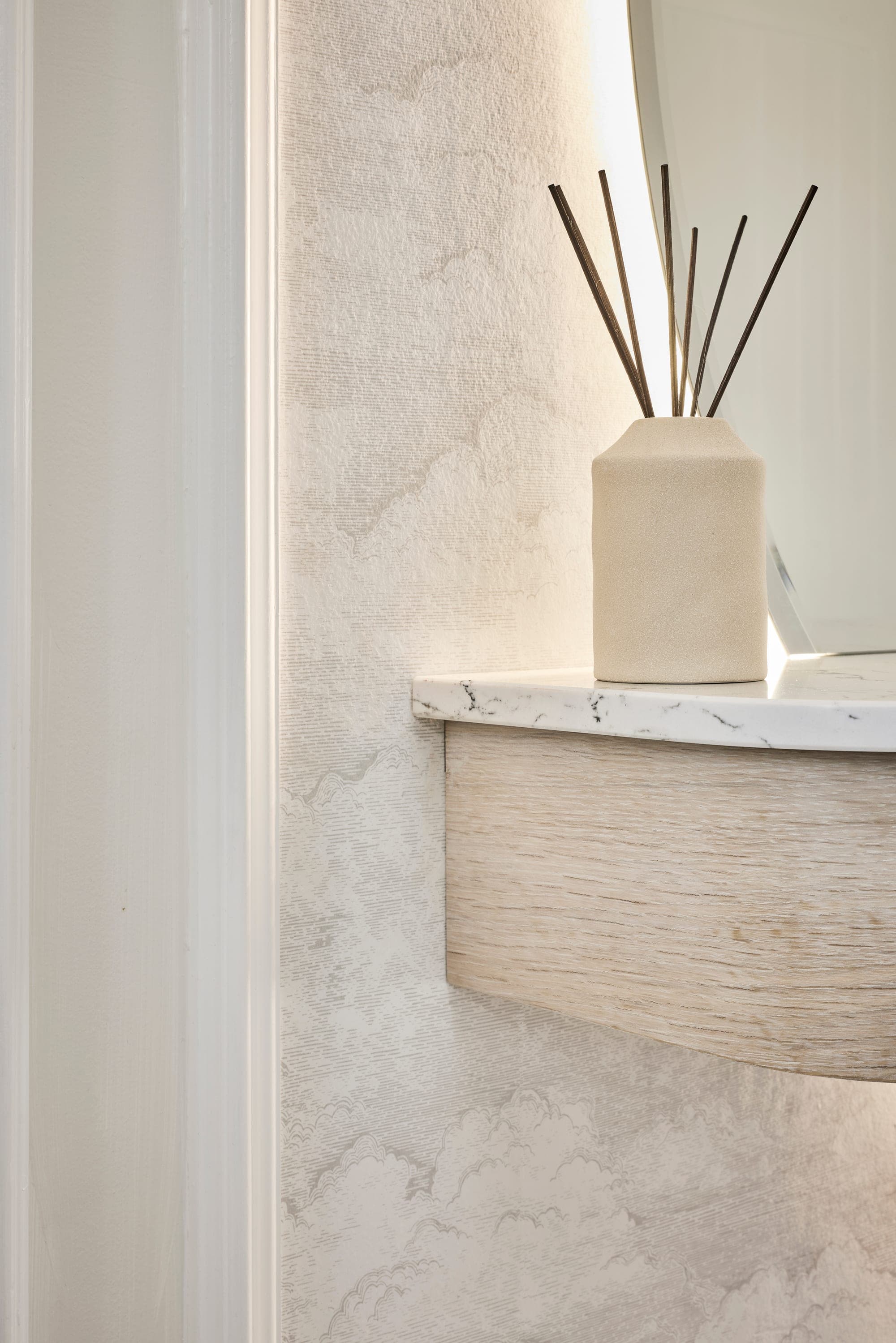 A bespoke curved vanity with a marble top and backlit mirror in a Wilmslow cloakroom
