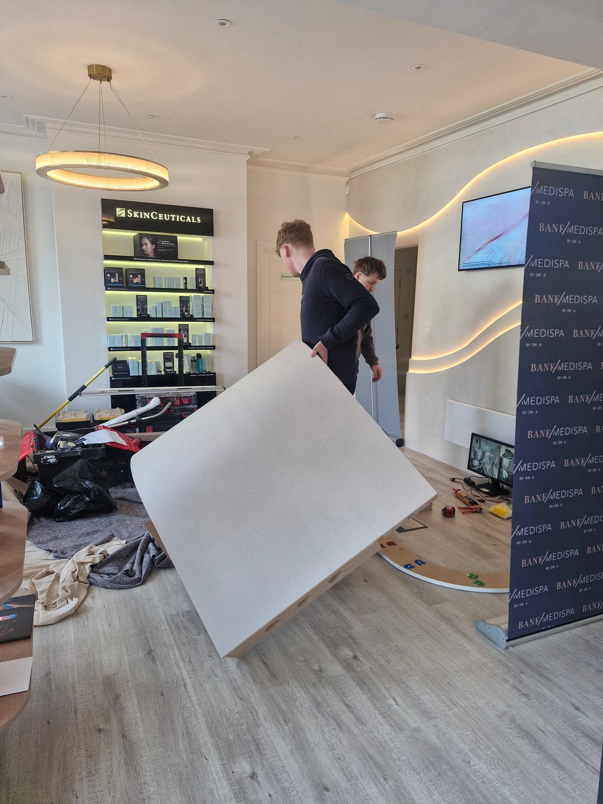 A curved reception desk panel being carried into Bank Medi Spa