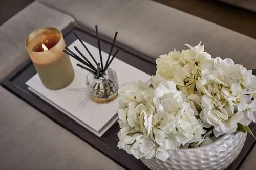 A styled tray detail with a candle, diffuser and fresh flowers