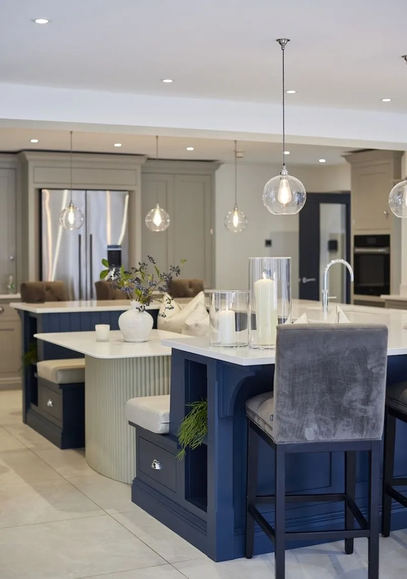 A marble kitchen island with bar stools and pendant lighting